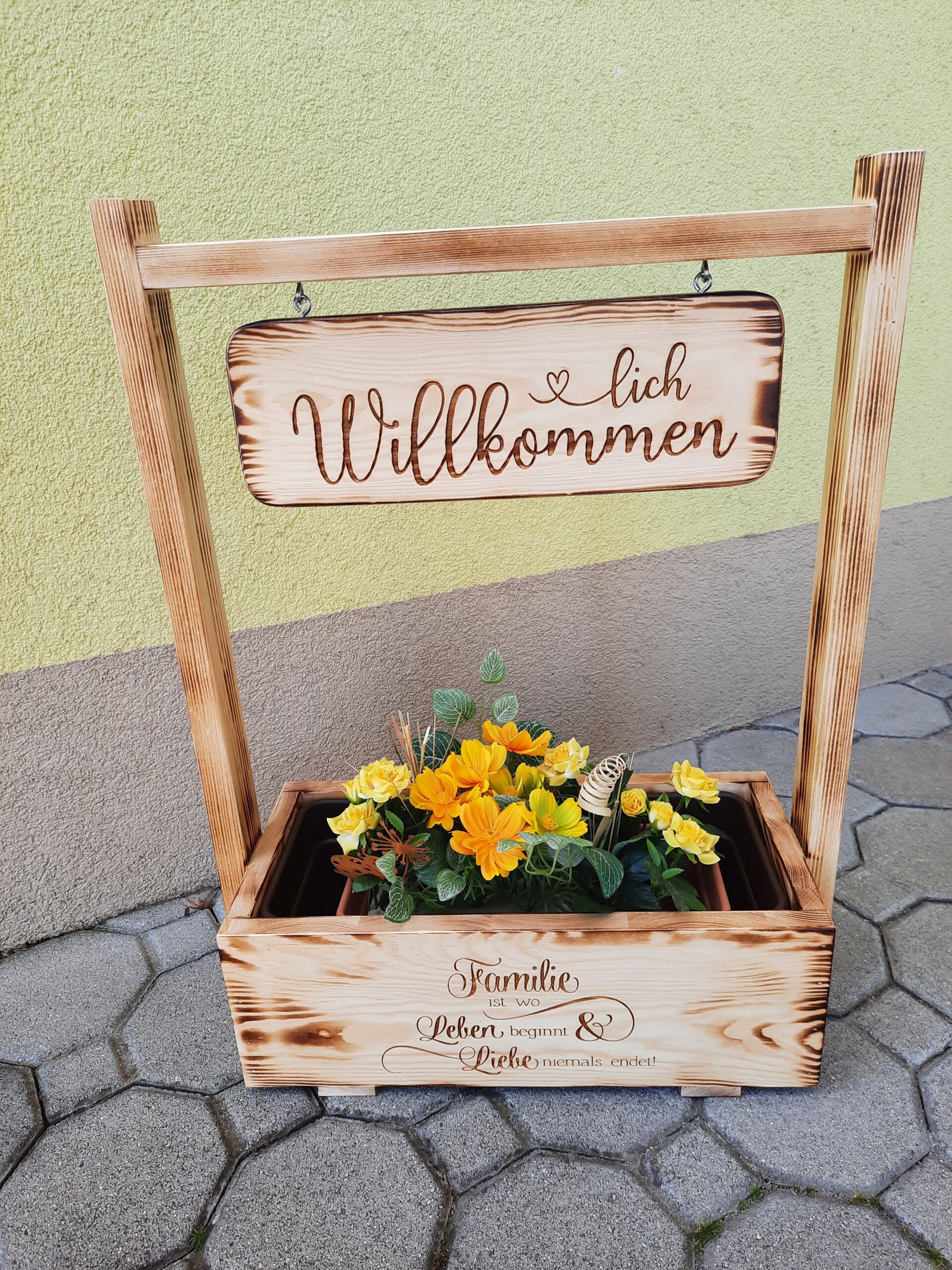 Holzaufsteller mit Blumenkisterl und Schild Herzlich Willkommen und Familie